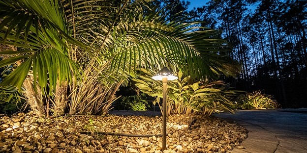 Path light with ornate light hat adorning a garden.