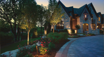 An opulent house gently illuminated with accent and path lights.