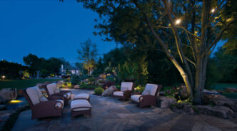 Landscape downlights illuminating a residential patio seating area at dusk.