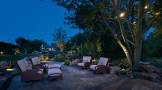 Landscape downlights illuminating a residential patio seating area at dusk.