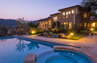 Backyard of an opulent home with a swimming pool, accent lights, path lights.