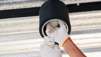 Person using gloves to remove a broken light bulb from a downlighting fixture.