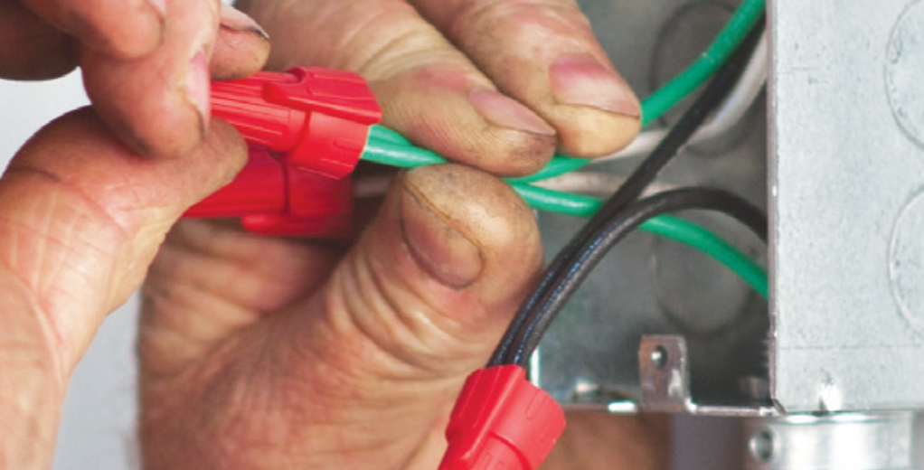 Person connecting wires with red king innovation wire nut connectors.