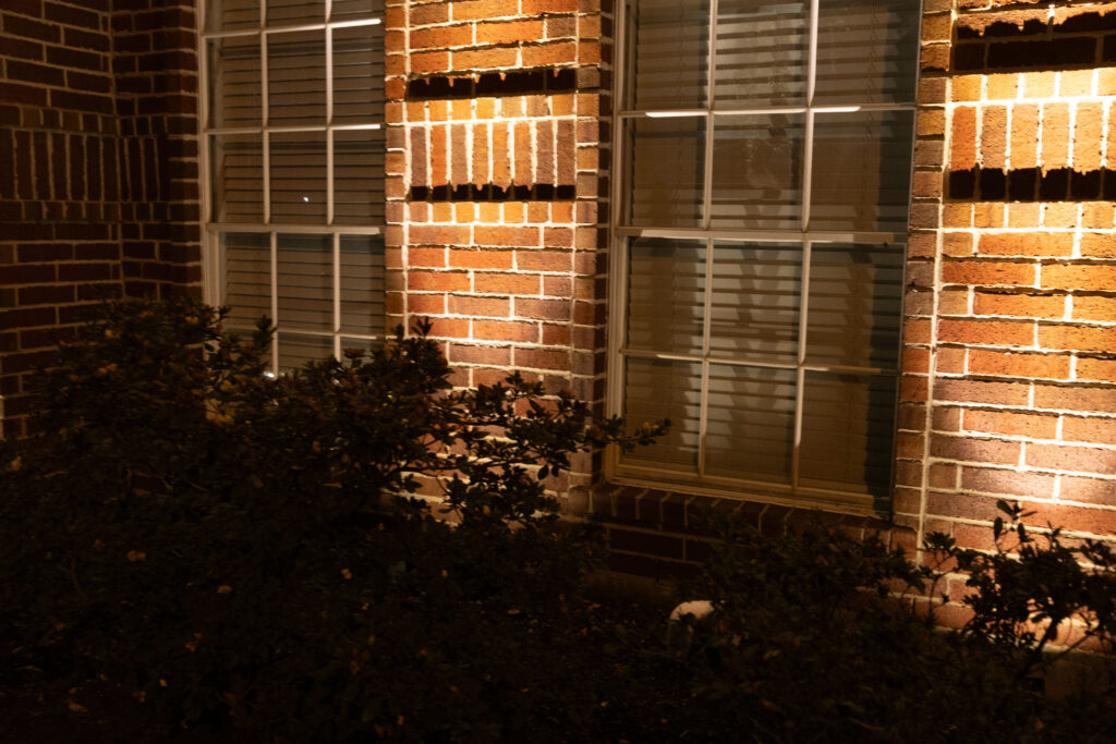 Accent lights for brick home uplighting window-adjacent textured brick design.