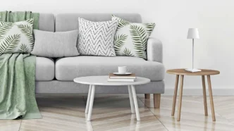 Portable white Zafferano Poldina Pro lamp resting on a stool next to a couch and coffee table.