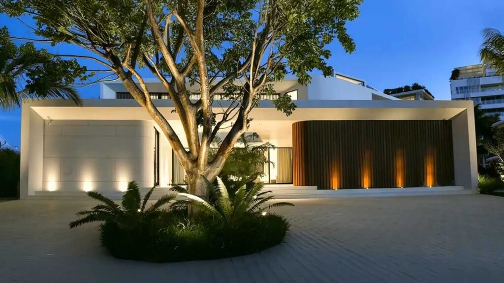 Kichler uplights illuminating a tree in front of a modern house lit by three bright uplights on the left and four less bright uplights on the right.
