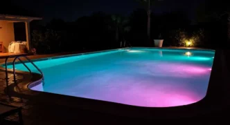 Swimming pool illuminated by pink underwater lights.