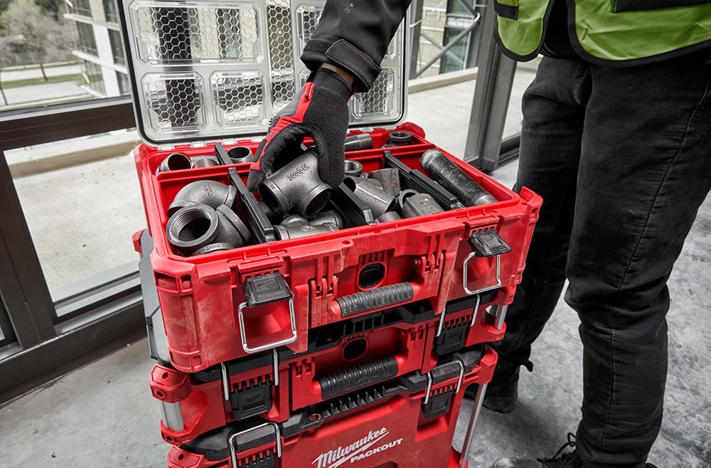 Person finding a black pvc pipe in the top compartment of a Milwaukee PACKOUT rolling tool box.