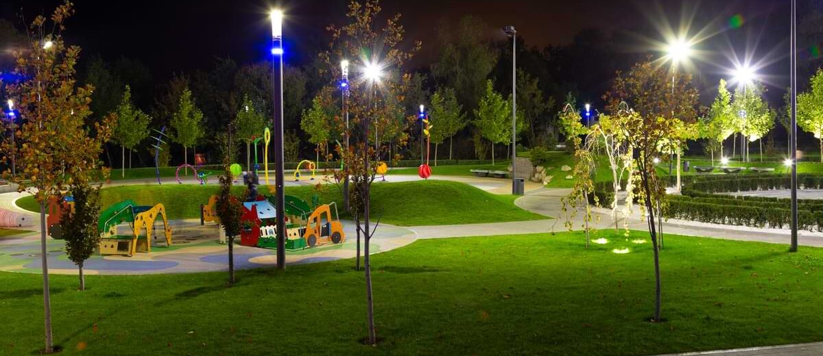 Lights shining throughout a playground adorned with colorful slides and amenities at night.