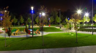 Lights shining throughout a playground adorned with colorful slides and amenities at night.