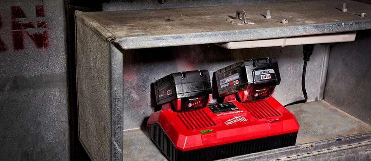 Milwaukee Dual Rapid Charger charging two Milwaukee Tool batteries on a work shelf.