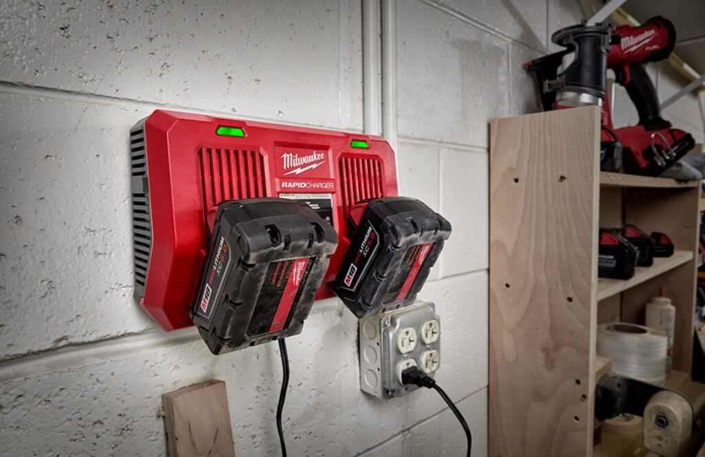 Milwaukee Dual Bay Charger mounted on a cinder block wall charging two Milwaukee batteries. 