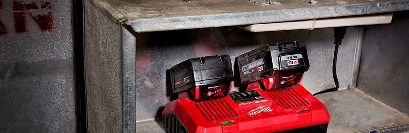 Milwaukee Dual Bay Charger tucked in a jobsite shelf charging two Milwaukee batteries.