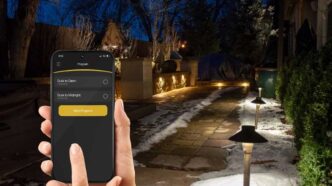 Person controlling landscape lighting with Alliance itPRO app.