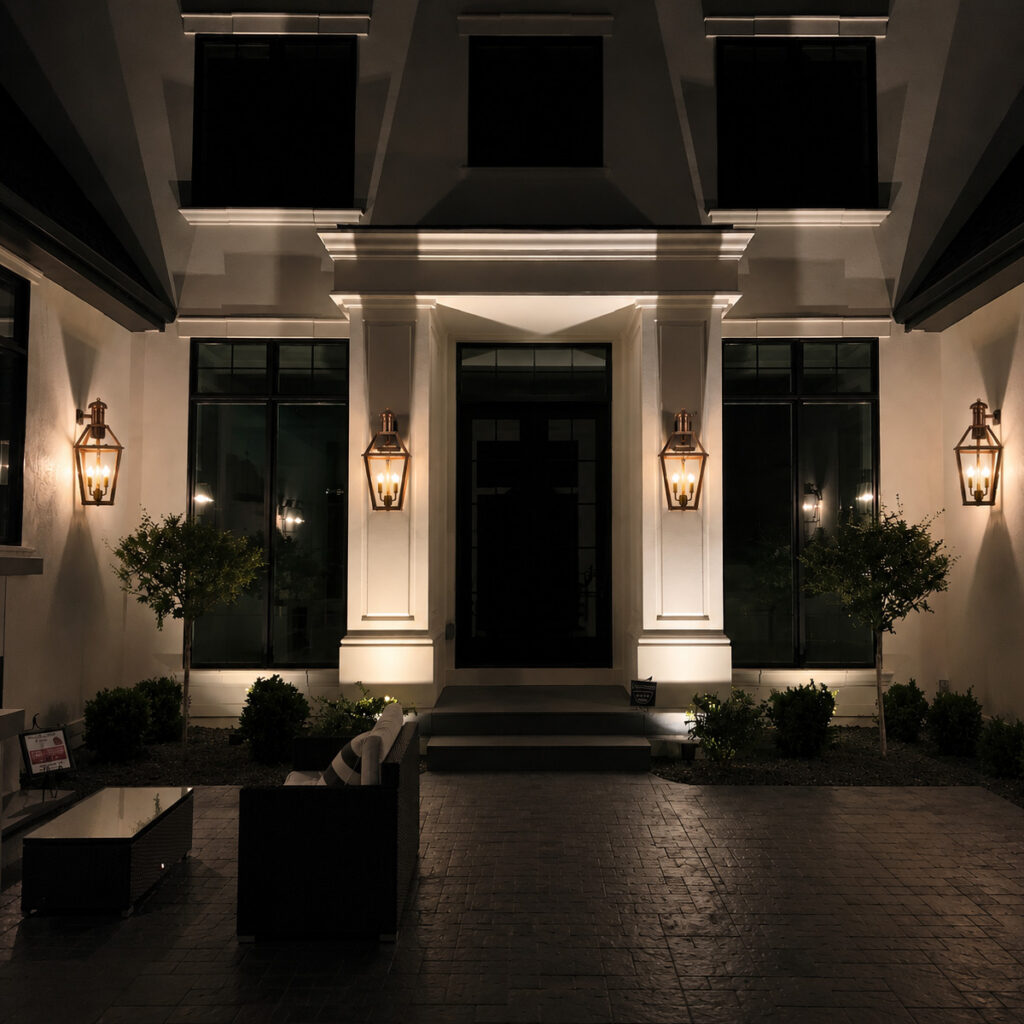 Large residential courtyard with outdoor coach lights mounted to the exterior between doors and windows.