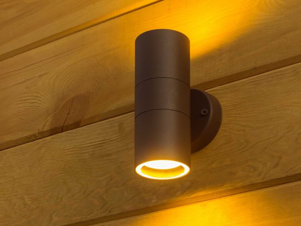 Bronze outdoor sconce light fashioned to wood panel exterior.