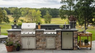 linear style outdoor kitchen with a scenic open space backdrop bordered by trees on a sunny day.